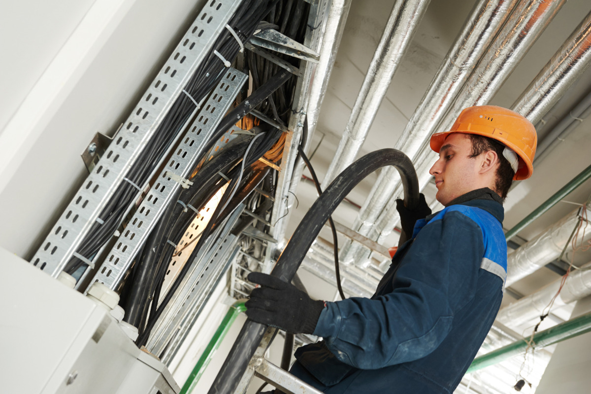 A man in a hard-hat working on large cabling